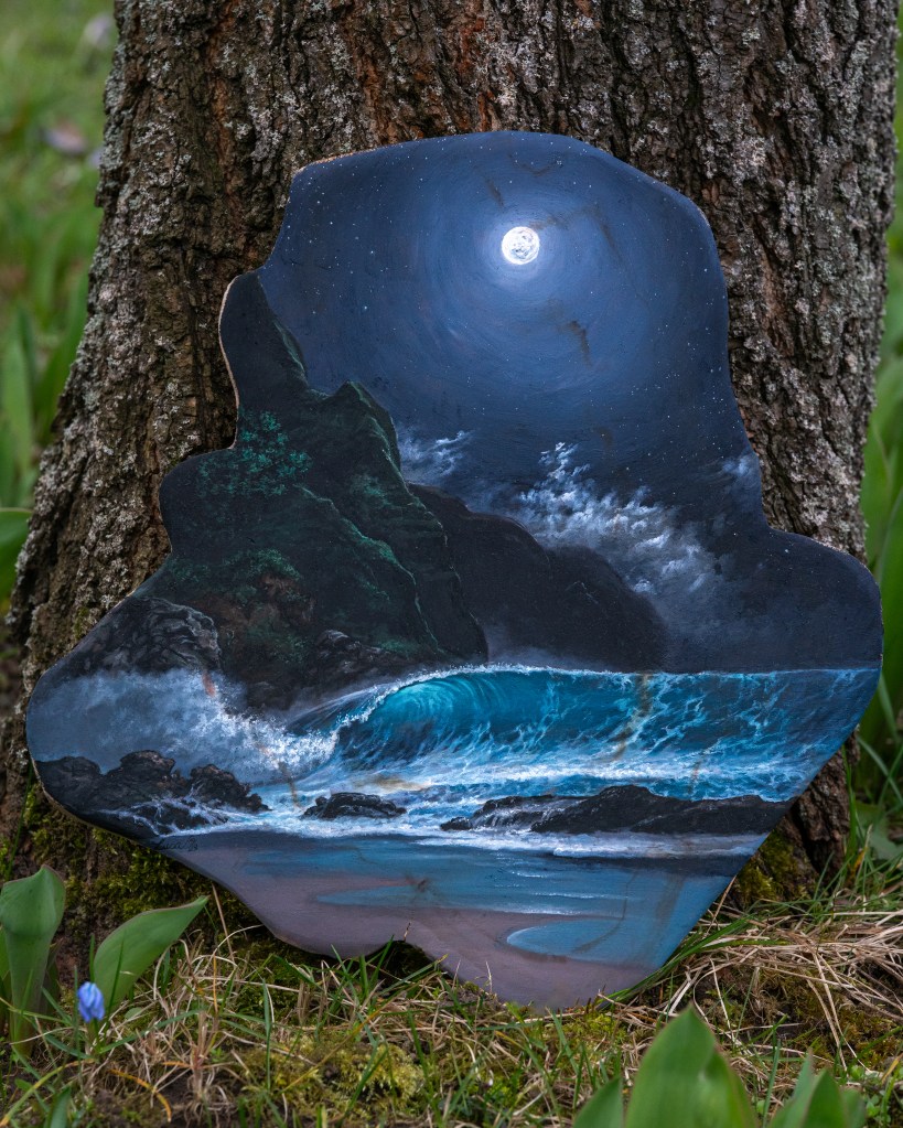 Eine Strandszenerie bei Nacht. Eine große Welle bricht sich gerade an der felsigen Küste. Darüber steht der Vollmond